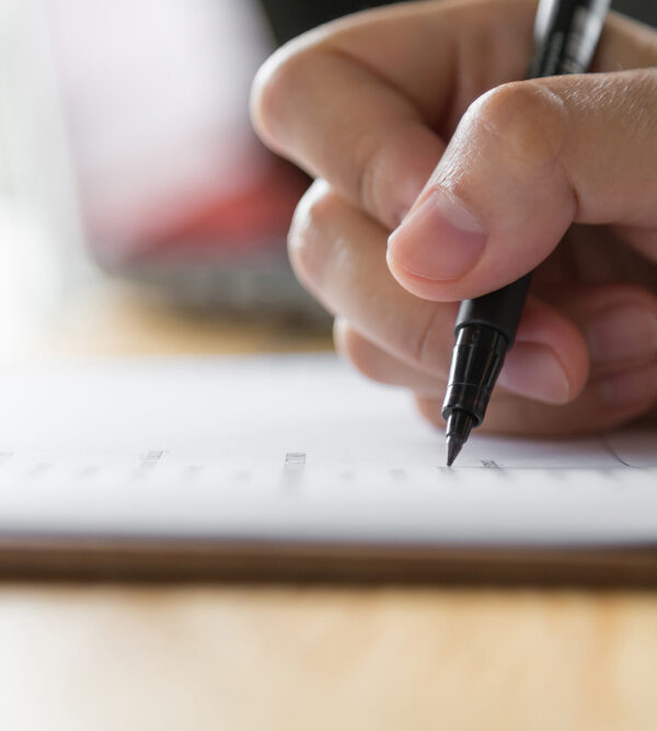 Hand holding a pen, writing on paper