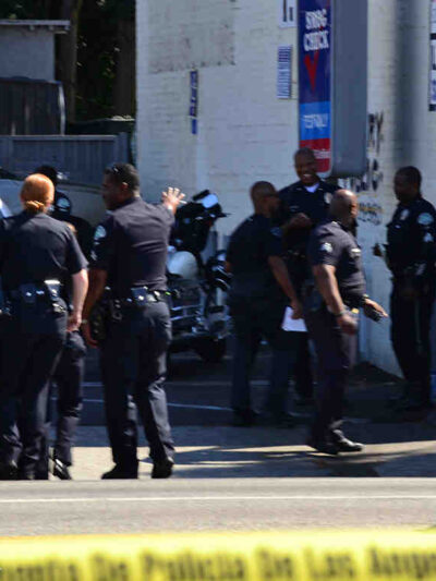 8 police officers standing on a street outside, yellow police tape in the foreground.