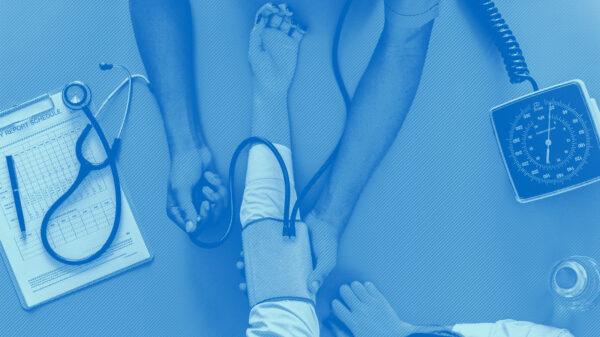 Birds eye view of the arms of a health care provider taking the blood pressure of a patient