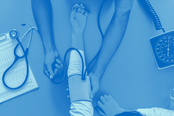 Birds eye view of the arms of a health care provider taking the blood pressure of a patient