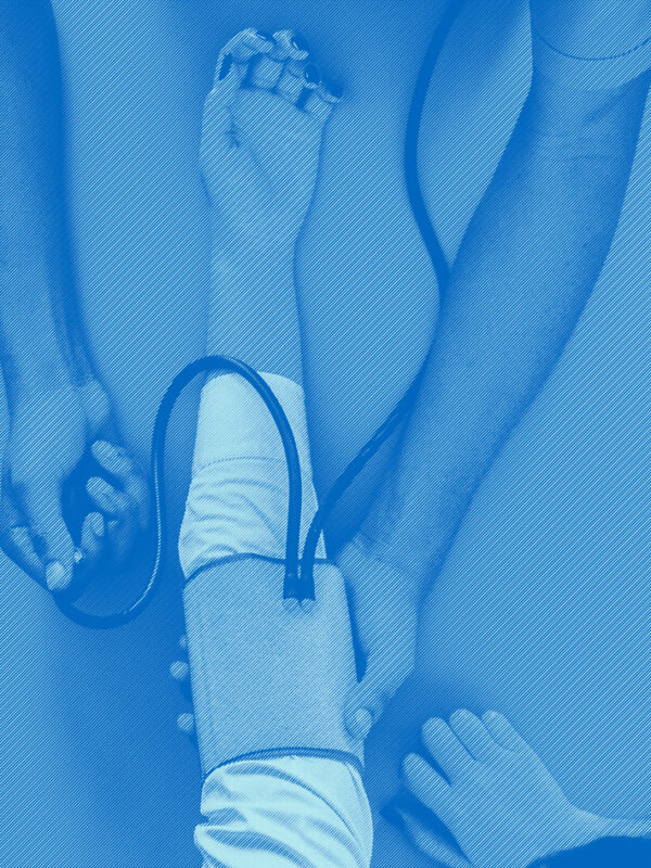 Birds eye view of the arms of a health care provider taking the blood pressure of a patient