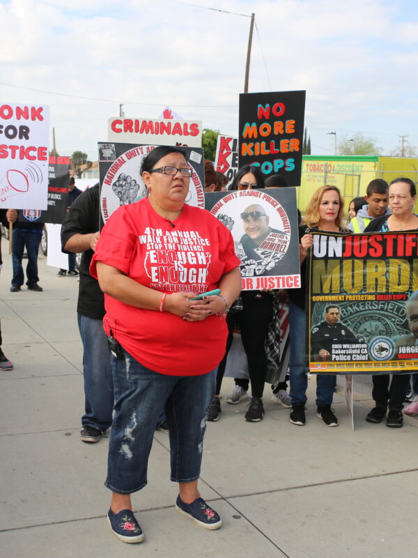 A group of people gathered on the sidewalk holding signs protesting police brutality