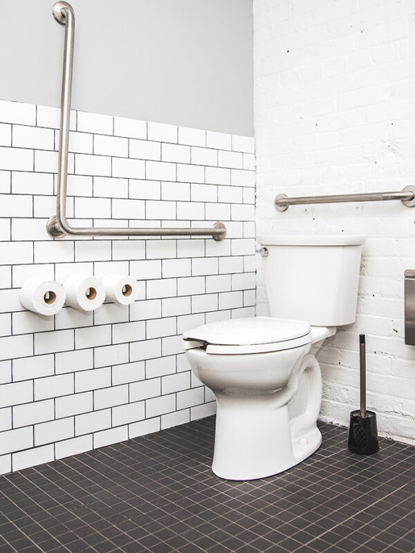 restroom stall with a toilet, toilet paper, grab bar