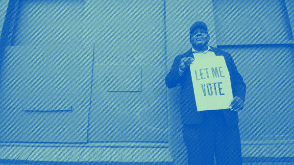A man holding a sign that reads: "Let Me Vote." Photo credit: Dorsey Nunn by Gigi Pandian, Let Me Vote Aug. 2014
