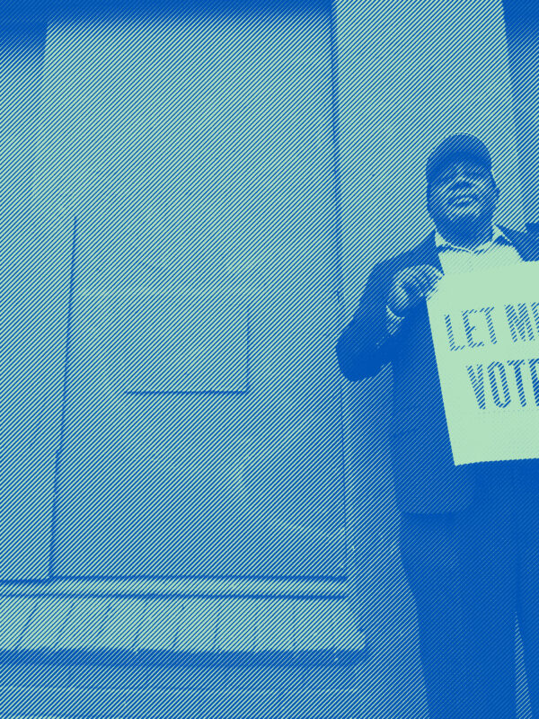 A man holding a sign that reads: "Let Me Vote." Photo credit: Dorsey Nunn by Gigi Pandian, Let Me Vote Aug. 2014