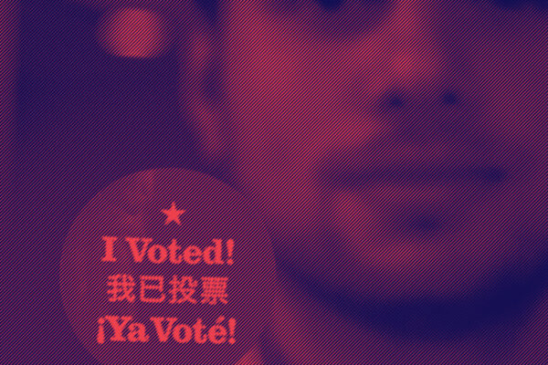 Man holding up a round sticker with text that reads: I voted!