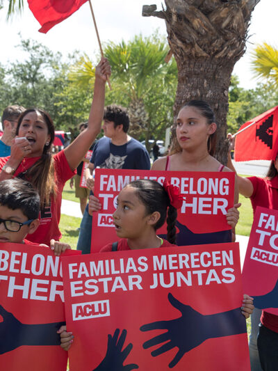 Demonstrators carrying signs with the text "Families Belong Together"