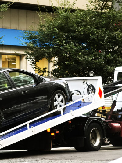 A black sedan on the truck bed of a towing truck