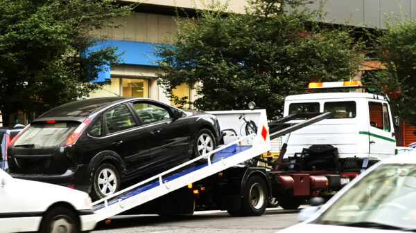 A black sedan on the truck bed of a towing truck