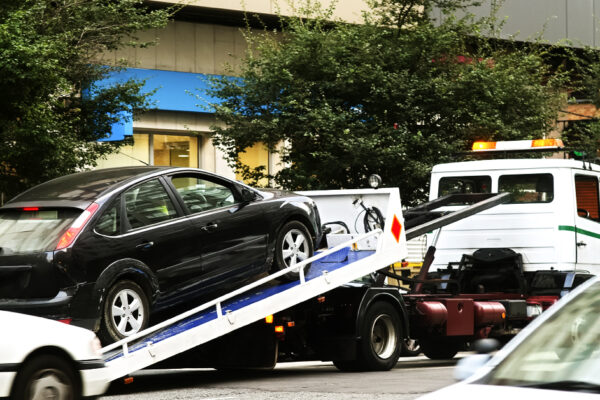 A black sedan on the truck bed of a towing truck