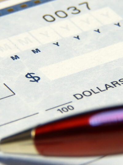 a blank check in the background, a pen in the foreground