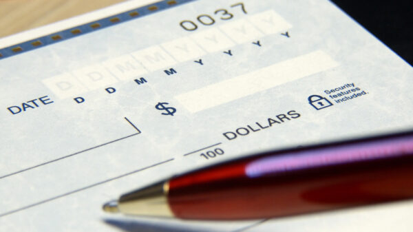 a blank check in the background, a pen in the foreground