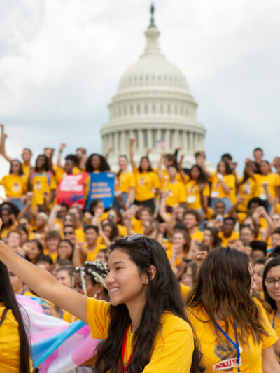 A group of young people wearing matching yellow shirts holding posters in favor of AB 392. They are marching to the California state Capitol.