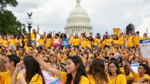 A group of young people wearing matching yellow shirts holding posters in favor of AB 392. They are marching to the California state Capitol.
