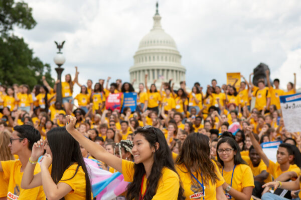A group of young people wearing matching yellow shirts holding posters in favor of AB 392. They are marching to the California state Capitol.