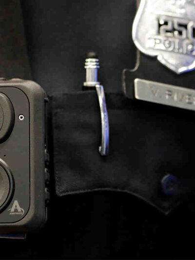 Police body camera pinned to the front of a police officer's shirt, a police badge to the left