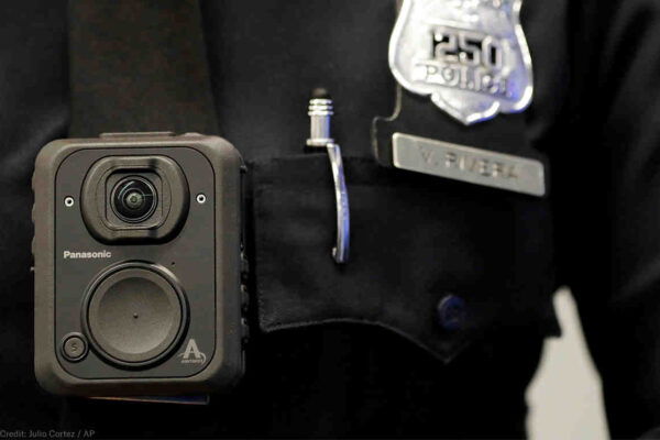 Police body camera pinned to the front of a police officer's shirt, a police badge to the left