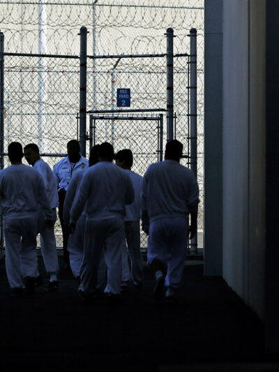 Detainees walk toward a fenced recreation area inside of an ICE detention facility in Washington state.