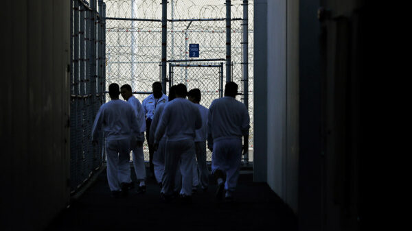 Detainees walk toward a fenced recreation area inside of an ICE detention facility in Washington state.