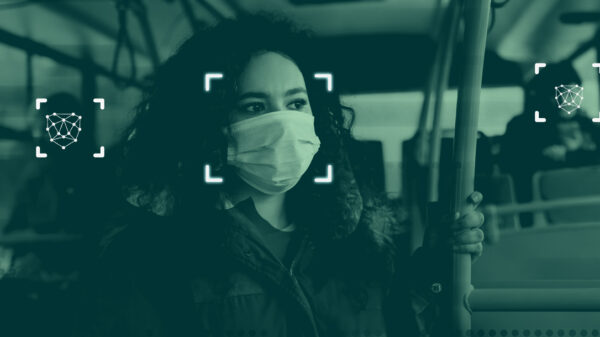 A simulation of facial recognition technology: a photograph of a woman on a public bus wearing a mask with graphics overlayed indicating that the software is scanning her face.