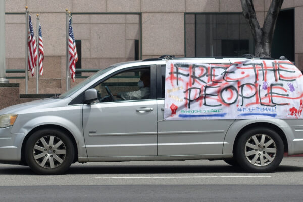 A silver van with a large hand-made sign on the side of the van that reads: Free the People, Check the Sheriff