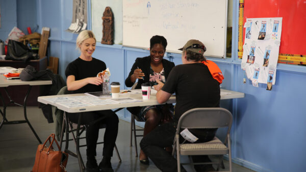 Three people sitting around a table at a community event working together.