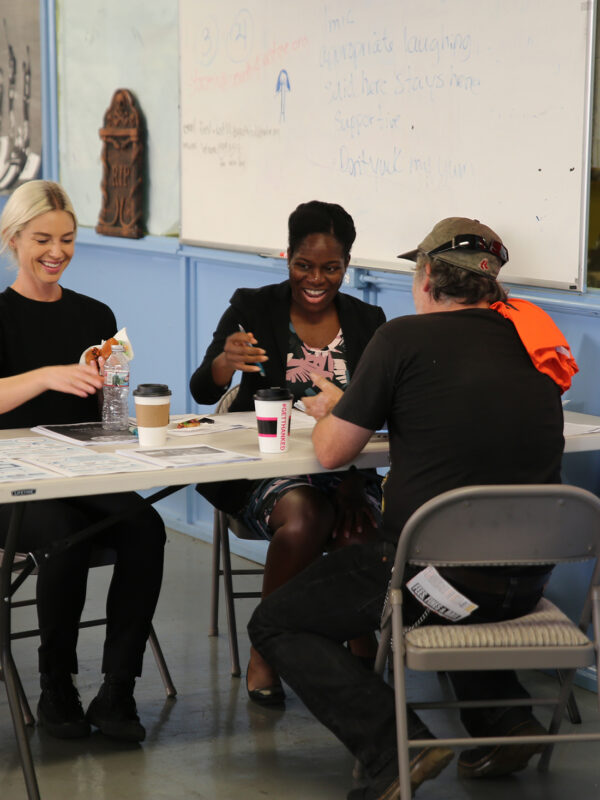 Three people sitting around a table at a community event working together.