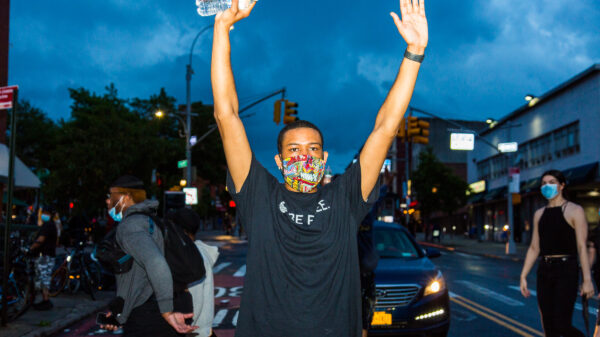 A man at a protest against police violence holding his hands in the air.