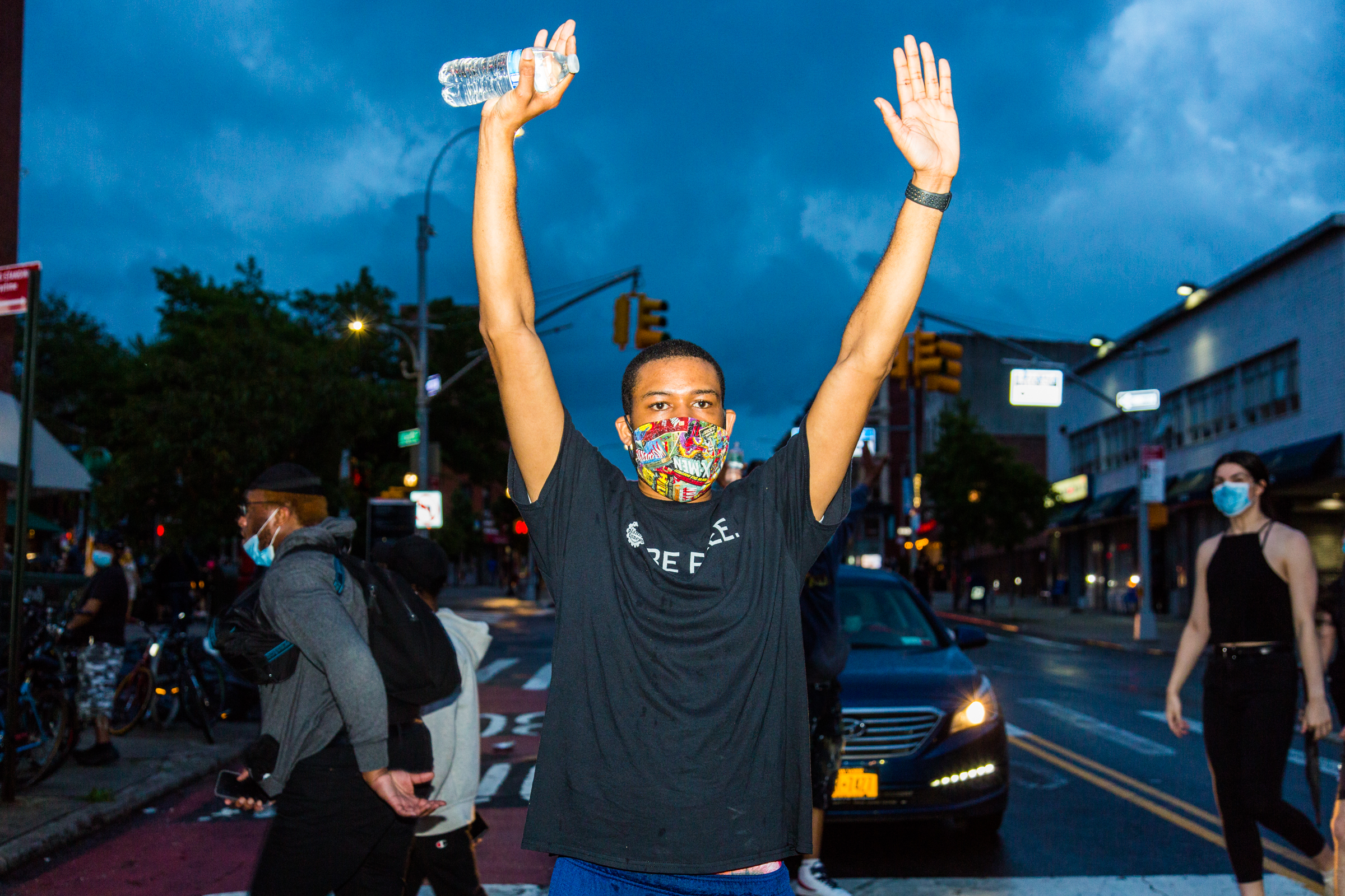 A man at a protest against police violence holding his hands in the air.