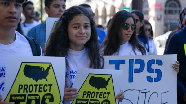 Crista Ramos and TPS rally attendees hold up signs that say, "Protect TPS."