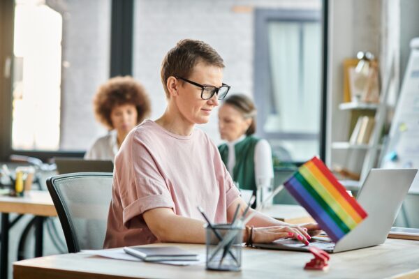 Person typing on laptop with rainbow flag