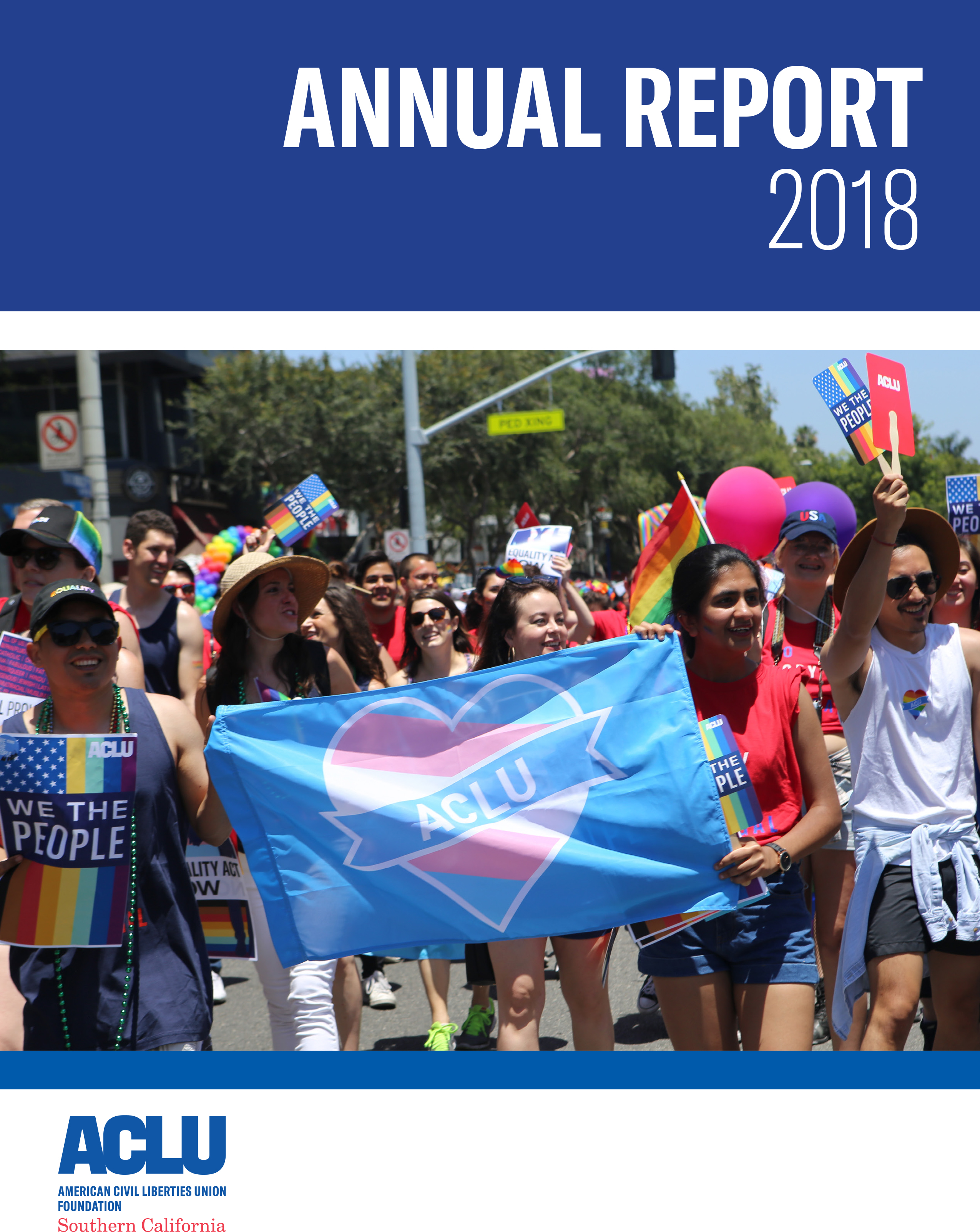 Annual Report 2018 ACLU of Southern California. Image of a group of people marching in the Los Angeles Pride Parade, the people in the front holding a blue flag with a pink and blue ACLU heart on it.
