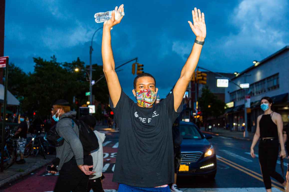 A man at a protest against police violence holding his hands in the air. 