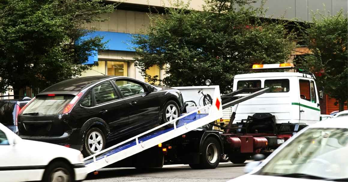 A black sedan on the truck bed of a towing truck