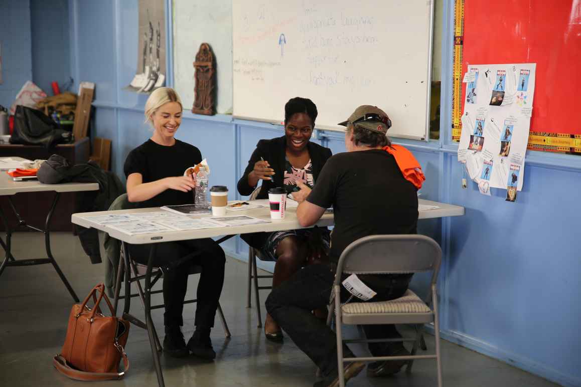 Three people sitting around a table at a community event working together.