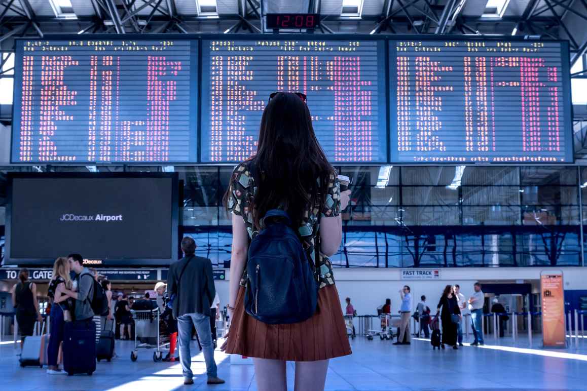 A woman at the airport looking up at the arrivals/departures board