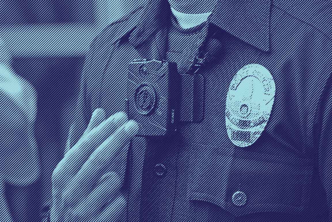 Close up photo of a police man wearing a body camera near his lapel, next to his police badge