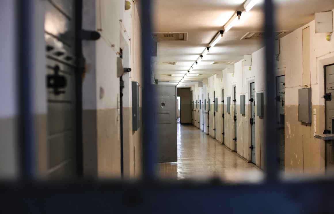a hallway inside a jail showing a row of locked doors