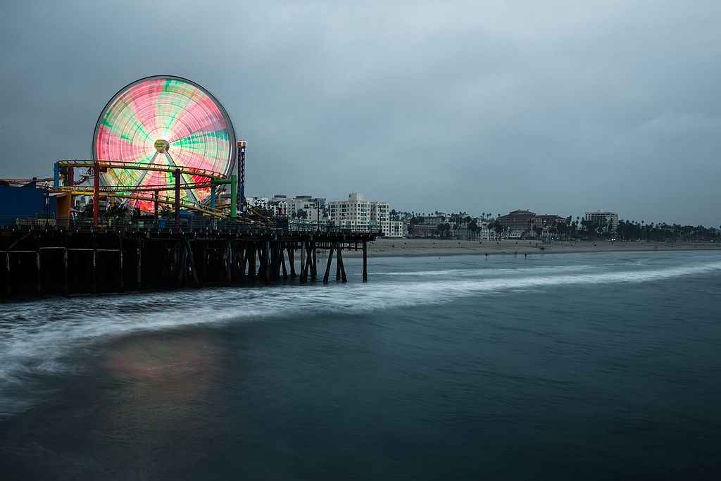 Timelapse photography of a lit-up ferris wheel at the Santa Monica Pier against a dark sky