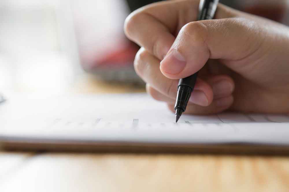 Hand holding a pen, writing on paper