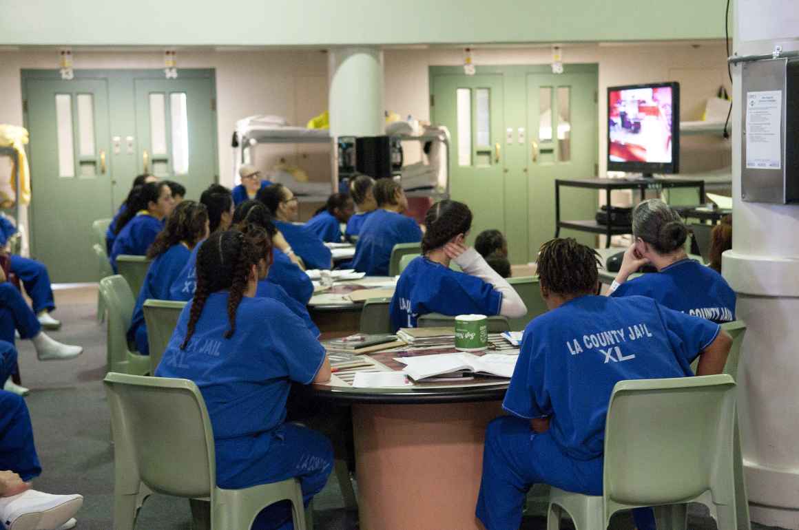 People experiencing incarceration at LA County Jails sitting in a recreation room looking at a TV screen