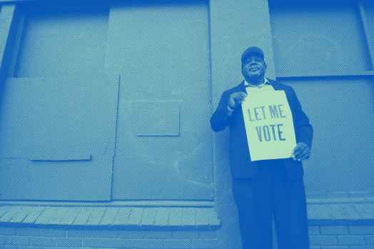 A man holding a sign that reads: "Let Me Vote." Photo credit: Dorsey Nunn by Gigi Pandian, Let Me Vote Aug. 2014