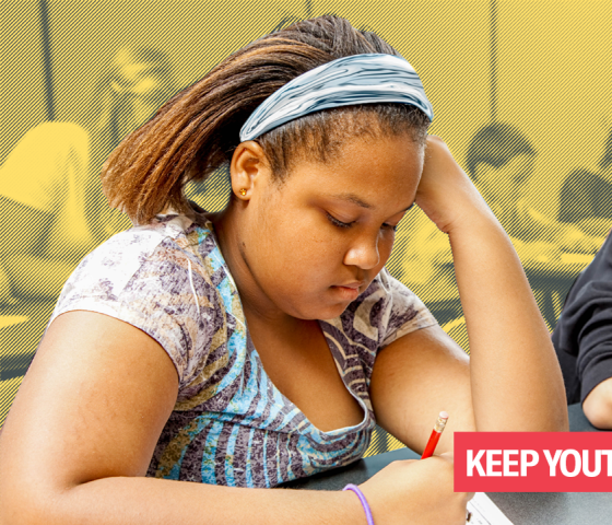 Image of a young Black girl and a young Afro-Latino boy sitting in a classroom writing.