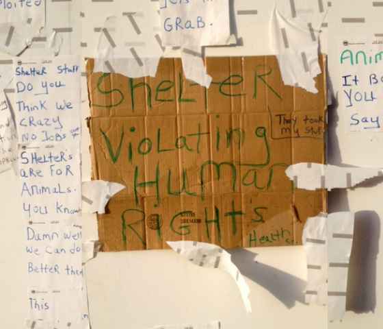 a sign handwritten on a piece of cardboard with text that reads: shelter violating human rights