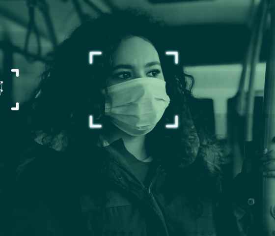 A simulation of facial recognition technology: a photograph of a woman on a public bus wearing a mask with graphics overlayed indicating that the software is scanning her face.