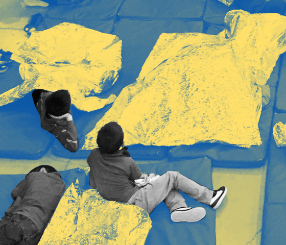 Children in a detention center sitting and laying on mats on the floor with only foil blankets for warmth