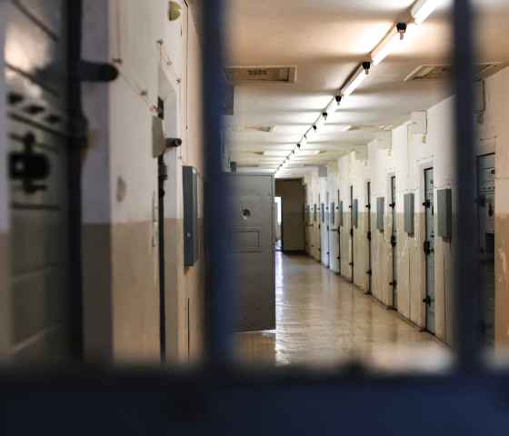 a hallway inside a jail showing a row of locked doors
