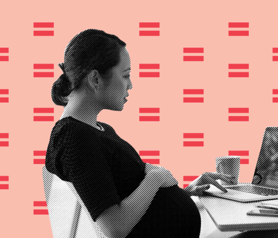 A pregnant woman sitting at a desk, working on a laptop
