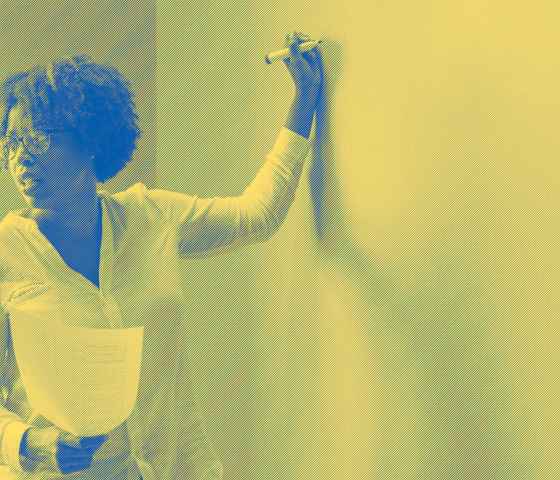 A woman standing and holding a marker to a white board